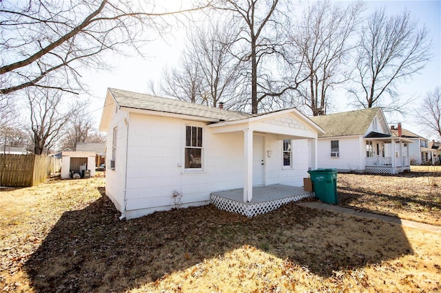 view of front of property featuring an outbuilding, covered porch, roof with shingles, and fence