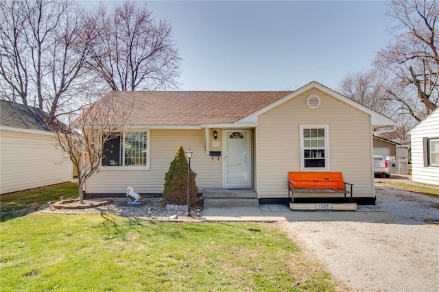 view of front facade with a front yard and a shingled roof