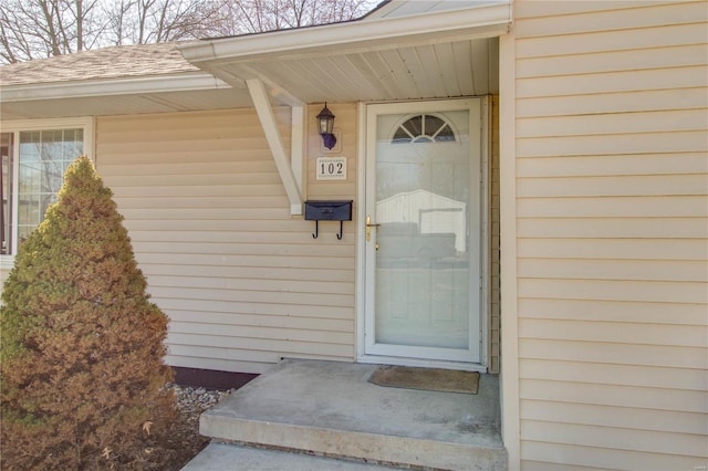 view of exterior entry with a shingled roof