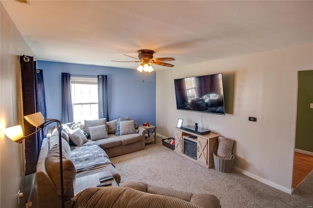 carpeted living room featuring baseboards and ceiling fan