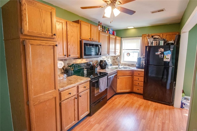 kitchen featuring visible vents, light countertops, light wood-style floors, black appliances, and a sink