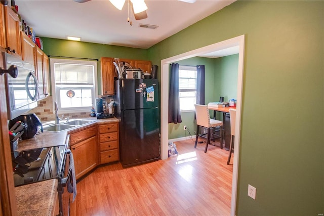 kitchen featuring visible vents, light wood-type flooring, appliances with stainless steel finishes, brown cabinetry, and a ceiling fan