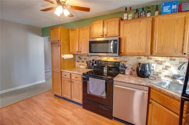 kitchen with ceiling fan, light countertops, appliances with stainless steel finishes, light wood-type flooring, and backsplash