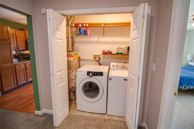 washroom with gas water heater, light colored carpet, washing machine and dryer, and laundry area