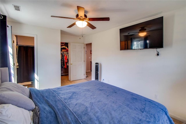 carpeted bedroom featuring visible vents, baseboards, a walk in closet, and ceiling fan