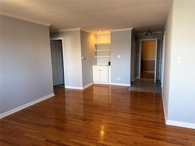 spare room with crown molding, baseboards, and wood finished floors