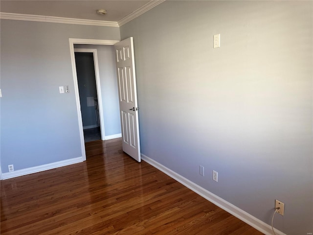 spare room featuring baseboards, dark wood-style floors, and crown molding