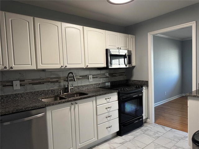 kitchen featuring dark stone countertops, a sink, stainless steel appliances, white cabinetry, and marble finish floor