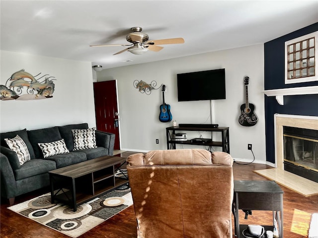 living room with wood finished floors, a ceiling fan, baseboards, and a premium fireplace