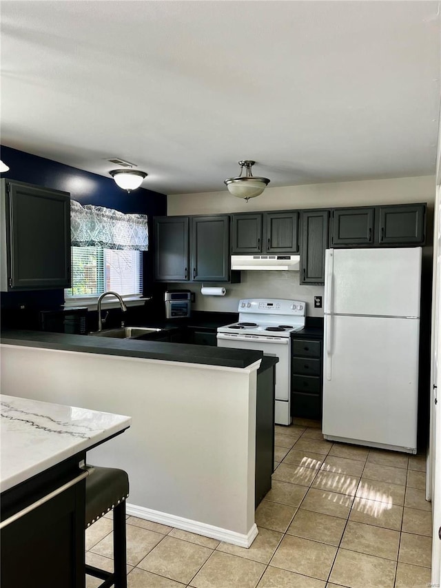 kitchen with a sink, white appliances, under cabinet range hood, and light tile patterned floors