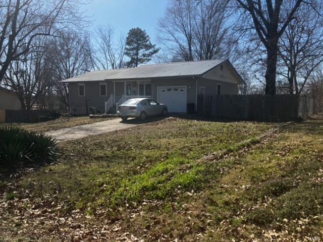 exterior space with a garage, metal roof, driveway, and fence