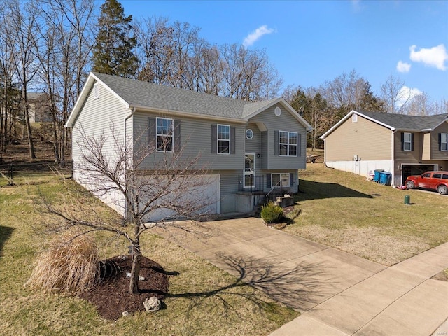 bi-level home featuring a front yard, concrete driveway, and an attached garage