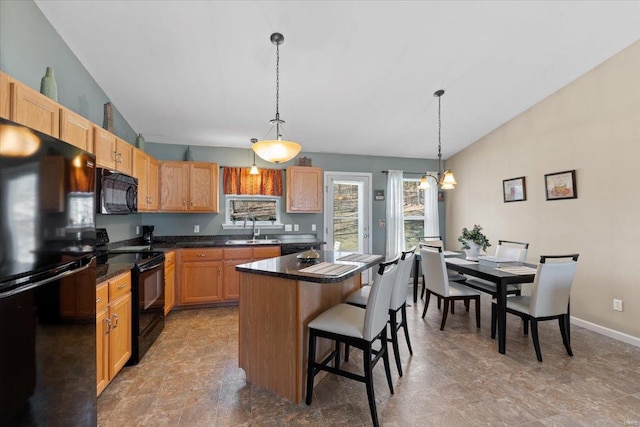 kitchen featuring a kitchen island, vaulted ceiling, a kitchen breakfast bar, black appliances, and a sink