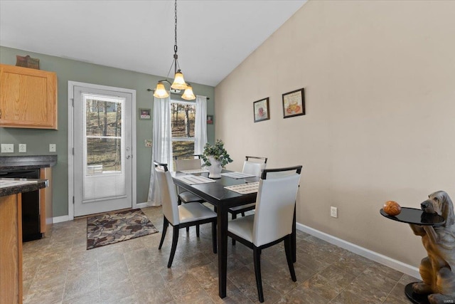 dining space featuring baseboards, stone finish floor, and vaulted ceiling