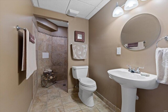 full bathroom with baseboards, tiled shower, and toilet