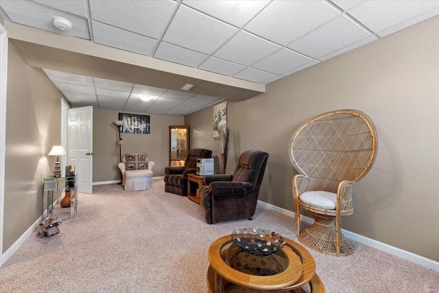 living area with carpet, baseboards, and a drop ceiling