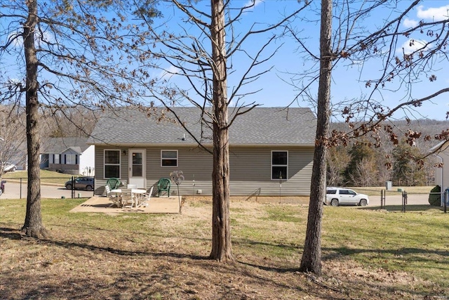 rear view of property with a yard, a patio, and a shingled roof