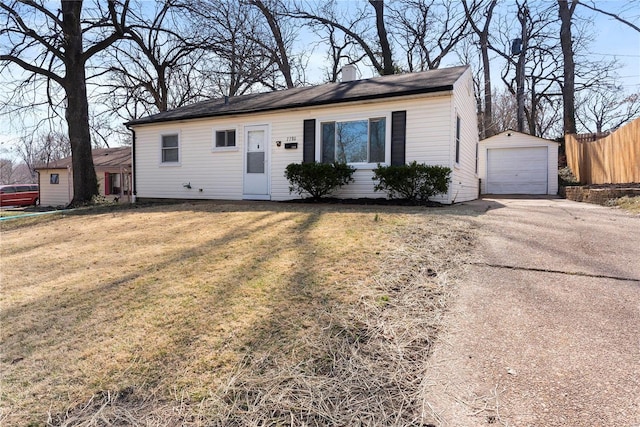 view of front of property featuring a front lawn, a detached garage, fence, an outdoor structure, and concrete driveway