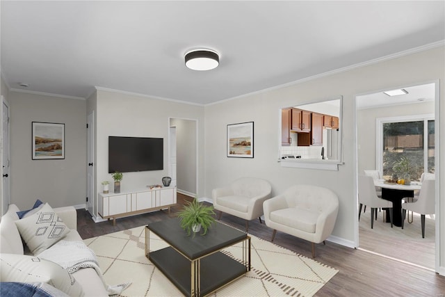 living area with baseboards, wood finished floors, and crown molding