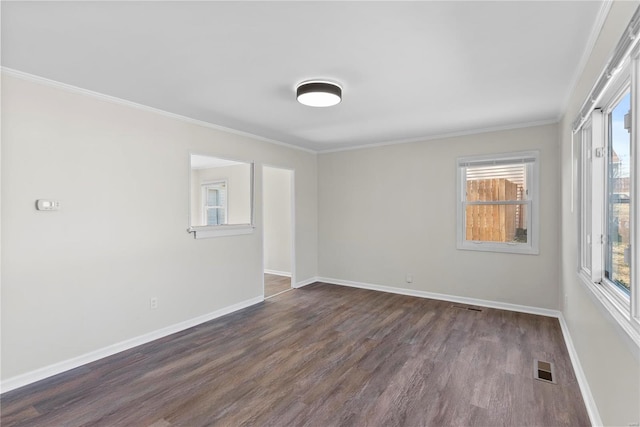 spare room featuring dark wood finished floors, visible vents, baseboards, and ornamental molding