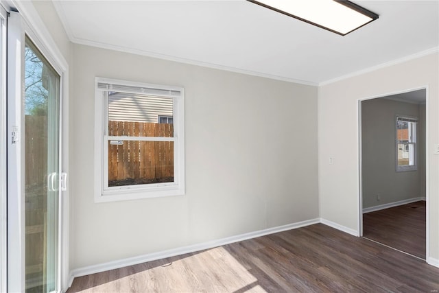 empty room with crown molding, dark wood-style floors, and baseboards