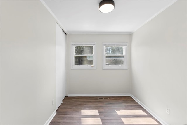 empty room featuring baseboards, wood finished floors, and ornamental molding