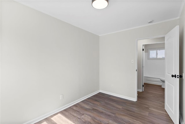 empty room with ornamental molding, baseboards, and dark wood-style flooring