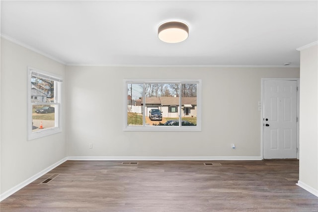 unfurnished room with wood finished floors, a healthy amount of sunlight, and visible vents