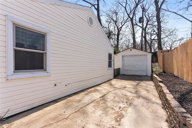 view of property exterior with concrete driveway, a detached garage, an outdoor structure, and fence