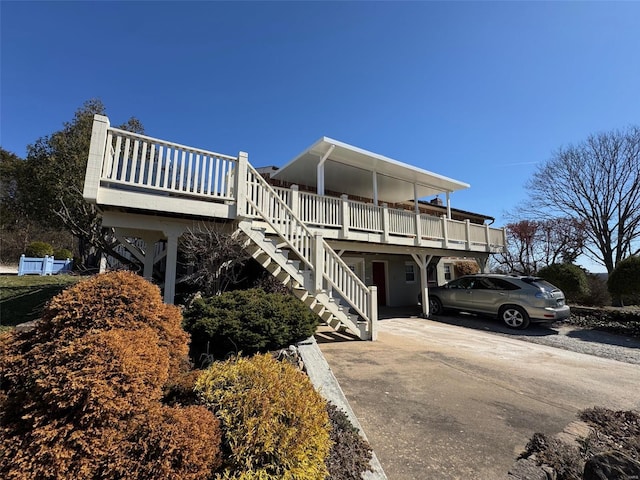 view of side of home featuring stairway, a wooden deck, and concrete driveway