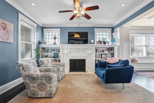 living area featuring a fireplace, crown molding, and a healthy amount of sunlight