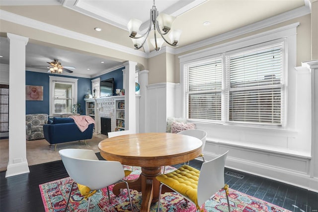 dining room with wood finished floors, a fireplace, and ornate columns