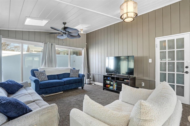 carpeted living room featuring lofted ceiling with skylight and ceiling fan