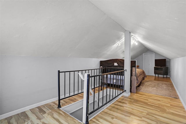 additional living space with lofted ceiling, wood finished floors, baseboards, and a textured ceiling