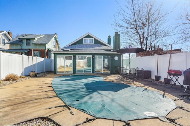 back of property featuring a fenced in pool, a shingled roof, a fenced backyard, and a patio area