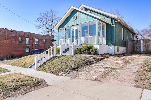 bungalow-style home featuring brick siding, stairway, covered porch, and board and batten siding