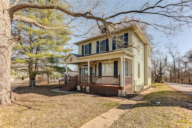 traditional style home with a porch, a front lawn, and fence