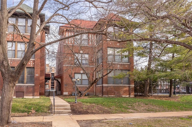 view of front of property with brick siding, a front lawn, and fence