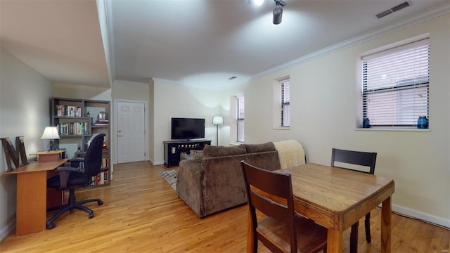 dining area with visible vents, crown molding, light wood-type flooring, and baseboards