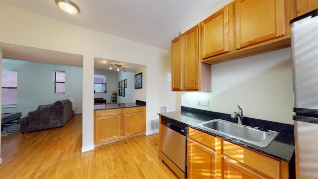 kitchen featuring light wood-type flooring, visible vents, a sink, dark countertops, and appliances with stainless steel finishes