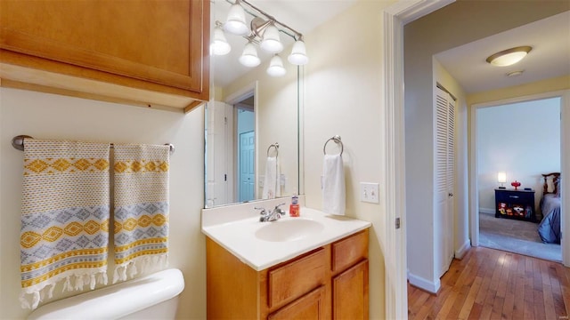 bathroom featuring vanity, toilet, baseboards, and hardwood / wood-style floors