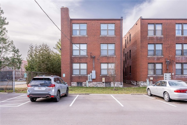 view of property featuring fence and uncovered parking