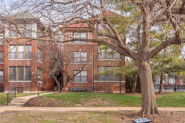 view of front of property featuring a front yard, fence, and brick siding