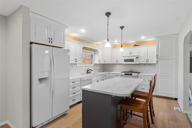 kitchen featuring white cabinets, white appliances, and light wood-style floors