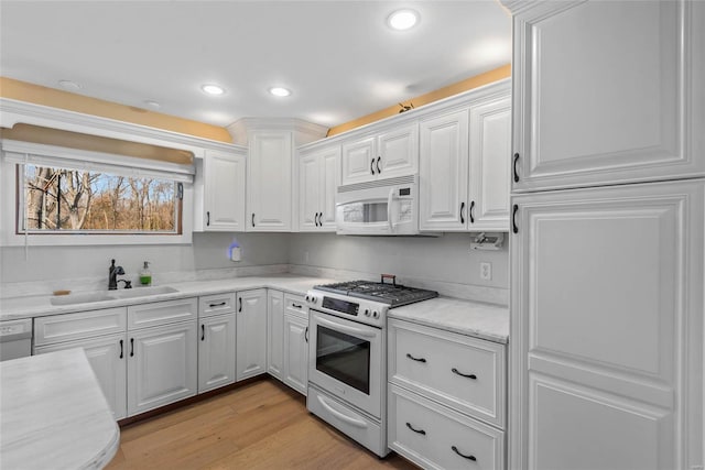 kitchen featuring a sink, range with gas stovetop, white cabinets, light countertops, and white microwave