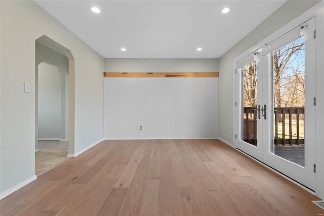 unfurnished room with recessed lighting, french doors, arched walkways, and light wood finished floors