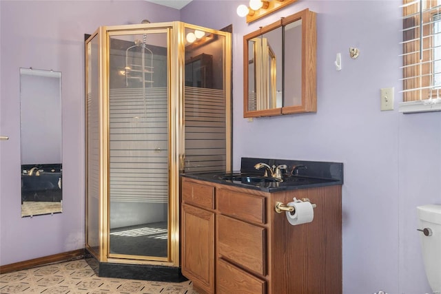 bathroom with baseboards, vanity, toilet, and a shower stall