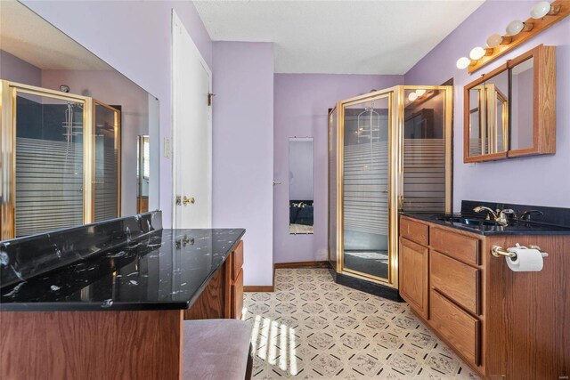 bathroom with tile patterned floors, a shower stall, vanity, and baseboards