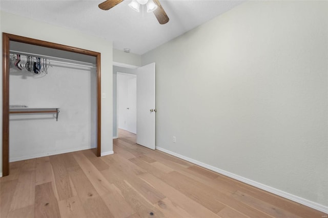 unfurnished bedroom featuring a closet, a ceiling fan, baseboards, and wood finished floors