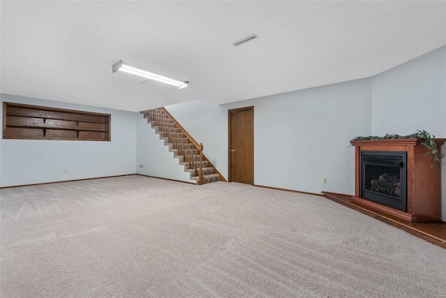 unfurnished living room featuring stairs, carpet, visible vents, and a fireplace with raised hearth